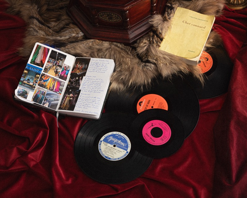 Disques vinyles et carnet de collages posés sur une fourrure et du velours rouge
