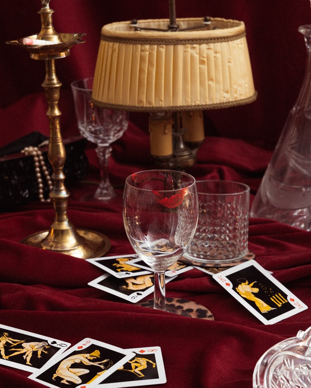 Nature morte : lampe, verres en cristal et cartes sur velours bordeaux
